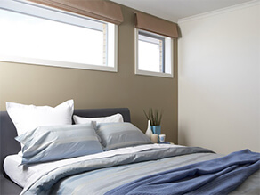 Khaki feature wall bedroom white ceiling with blue bed covers and pillows with plant and vase